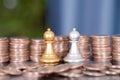 Stacks of dollar coins before the two chess pieces of both sides in a duel Royalty Free Stock Photo