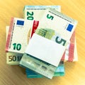 Stacks of Euro bills on a pine desk with a blank lable Royalty Free Stock Photo