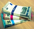 Stacks of Euro bills on a pine desk in fives, tens and twenties Royalty Free Stock Photo