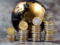 stacks of euro and cent coins symbolize a price increase in front of a black and gold globe Royalty Free Stock Photo