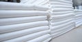 Stacks of folded white fabrics or sheets in an industrial laundry