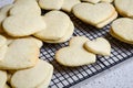 Stacks of heart shaped sugar cookies on a black wire cooling rack, granite kitchen counter Royalty Free Stock Photo