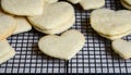 Stacks of heart shaped sugar cookies on a black wire cooling rack, granite kitchen counter Royalty Free Stock Photo