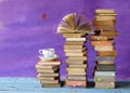 Stacks of multicolored books and an open book plus a cup of coffee. Reading, education, literature, learning, book fair Royalty Free Stock Photo