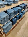 Stacks in perspective of modern jeans of different sizes and shades. A wide selection of jeans in a clothing store. Racks with