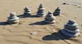 Stacks of smooth, round stones balance on a sandy beach. Each cairn varies in height Royalty Free Stock Photo