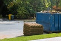 Stacks of sod rolls for new lawn and dumpster full garbage container residential construction home Installation of a modern