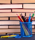 stacks of various hardback books and blue stationery glass with multi-colored wooden pencils