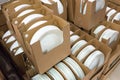 Stacks of white and round shaped porcelain plates in boxes.