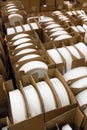 Stacks of white and round shaped porcelain plates in boxes.