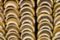 Stacks of yellow ceramic glazed curved roof tiles in a symmetrical pattern