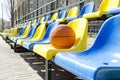 Stadium seats and basketball ball on it.Empty seats for fans at the sport court Royalty Free Stock Photo