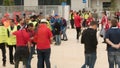 Stadium stewards standing in front of gate before game, spectators moving around