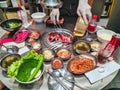 Staff is grilling sliced marinated pork on charcoal stove with korean side dishes and pickles Royalty Free Stock Photo