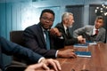 Staff meeting. Portrait of handsome african businessman in formal wear and eyeglasses looking at camera while sitting at Royalty Free Stock Photo