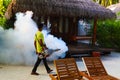 Staff member of Medhufushi Island Resort spraying garden in Maldives.