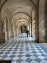 Staff member walks down long arched hallway in Versailles Palace