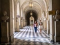 Staff members walk down Versailles Palace corridor, France.