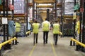 Staff in reflective vests walking from camera in a warehouse Royalty Free Stock Photo