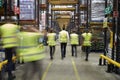 Staff in reflective vests walking in a warehouse, back view Royalty Free Stock Photo