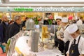 Staff serving customers at a food bar in Canary Wharf with Waitrose supermarkets in the background