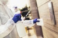 Staff using disinfectant from the bottle spraying an elevator push button control panel.