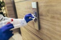 Staff using disinfectant from the bottle spraying an elevator push button control panel. Royalty Free Stock Photo