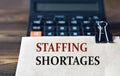 STAFFING SHORTACES - words on light brown paper on calculator background Royalty Free Stock Photo