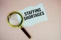 Staffing Shortages text written on paper torn top view on pink background Royalty Free Stock Photo