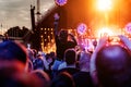 Stage lights against a happy woman with raised arms while enjoying a concert at a music festival Royalty Free Stock Photo