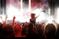 Stage lights against a happy woman with raised arms while enjoying a concert at a music festival Royalty Free Stock Photo