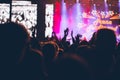 Stage lights and crowd of audience with hands raised at a music festival. Fans enjoying the party vibes