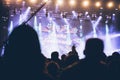 Stage lights and crowd of audience with hands raised at a music festival. Fans enjoying the party vibes