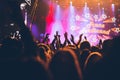 Stage lights and crowd of audience with hands raised at a music festival. Fans enjoying the party vibes