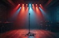Stage with microphone stand and spotlight in dimly lit venue. Empty tables and chairs on either side. Red and blue lights shine Royalty Free Stock Photo