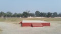 Stage with play ground & rhree boys in the field trees baundry are inside of ground & the sky has cleare