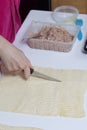 Stages of preparation of meat glomeruli. A woman slices thin strips of dough. Next to the table is a stuffing and lie tools Royalty Free Stock Photo