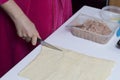 Stages of preparation of meat glomeruli. A woman slices thin strips of dough. Next to the table is a stuffing and lie tools Royalty Free Stock Photo