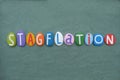 Stagflation, economic term composed with multi colored stone letters over green sand