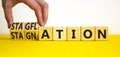 Stagflation or stagnation symbol. Businessman turns cubes, changes the word stagnation to stagflation. Beautiful yellow table