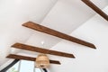 Stained brown decorative wooden beams in home living room white color ceiling.