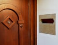Stained brown wooden entrance door with peephole and stone mail slot
