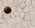 Stained circles of dried coffee from spills and splashes are seen on a table top