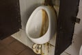 A stained and dirty urinal at an unmaintained and filthy public restroom