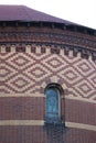 Stained glass arch window surrounded by red and cream diamond brick