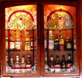 Liquor bottles blurred behind stained glass cabinet. Royalty Free Stock Photo