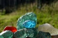 Stained glass from old glassworks smoothed and rounded in a mountain river collected by children beautifully stand out in the sun