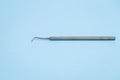 Stainless dental probe laying on light blue background