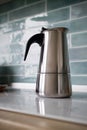 Stainless geyser coffee maker on a background of blue tiles