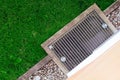 Stainless Grate of water Drain, gravel, stones and green grass lawn view from above Royalty Free Stock Photo